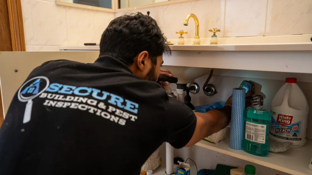 Inspector checking plumbing under a sink